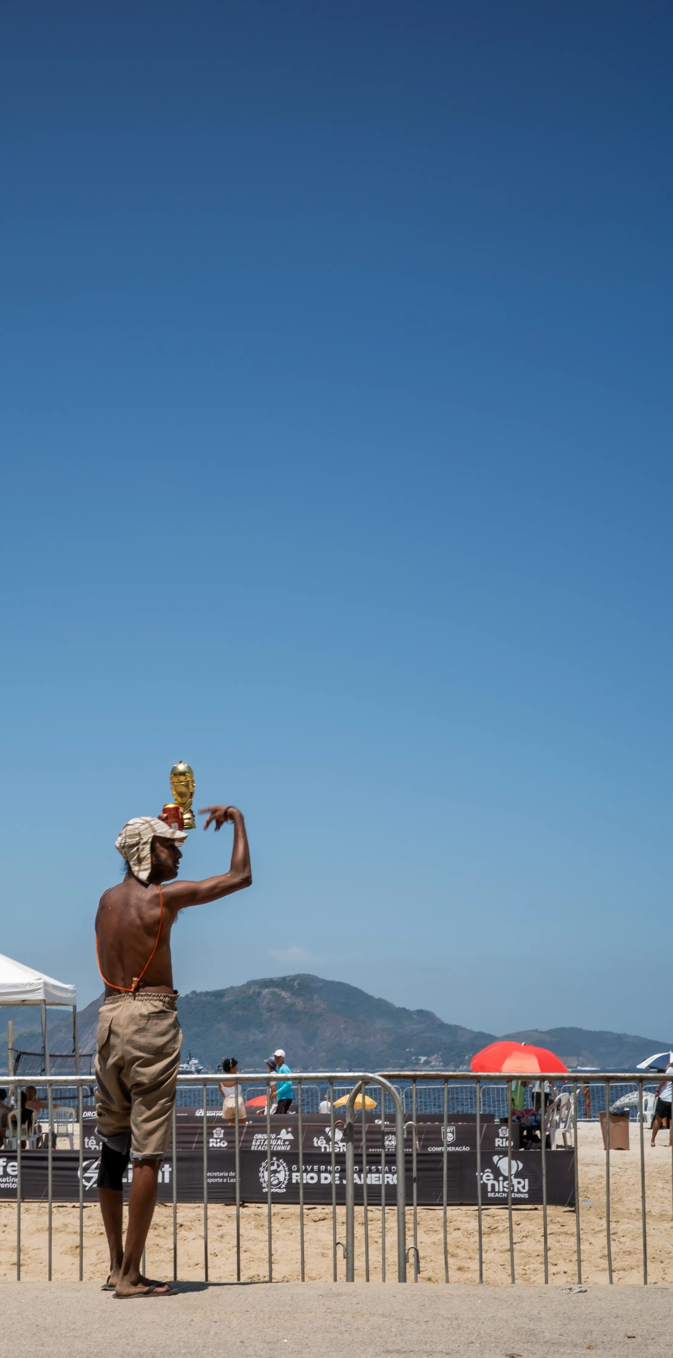 Street vendor balancing a World Cup trophy on his head at a Rio de Janeiro beach