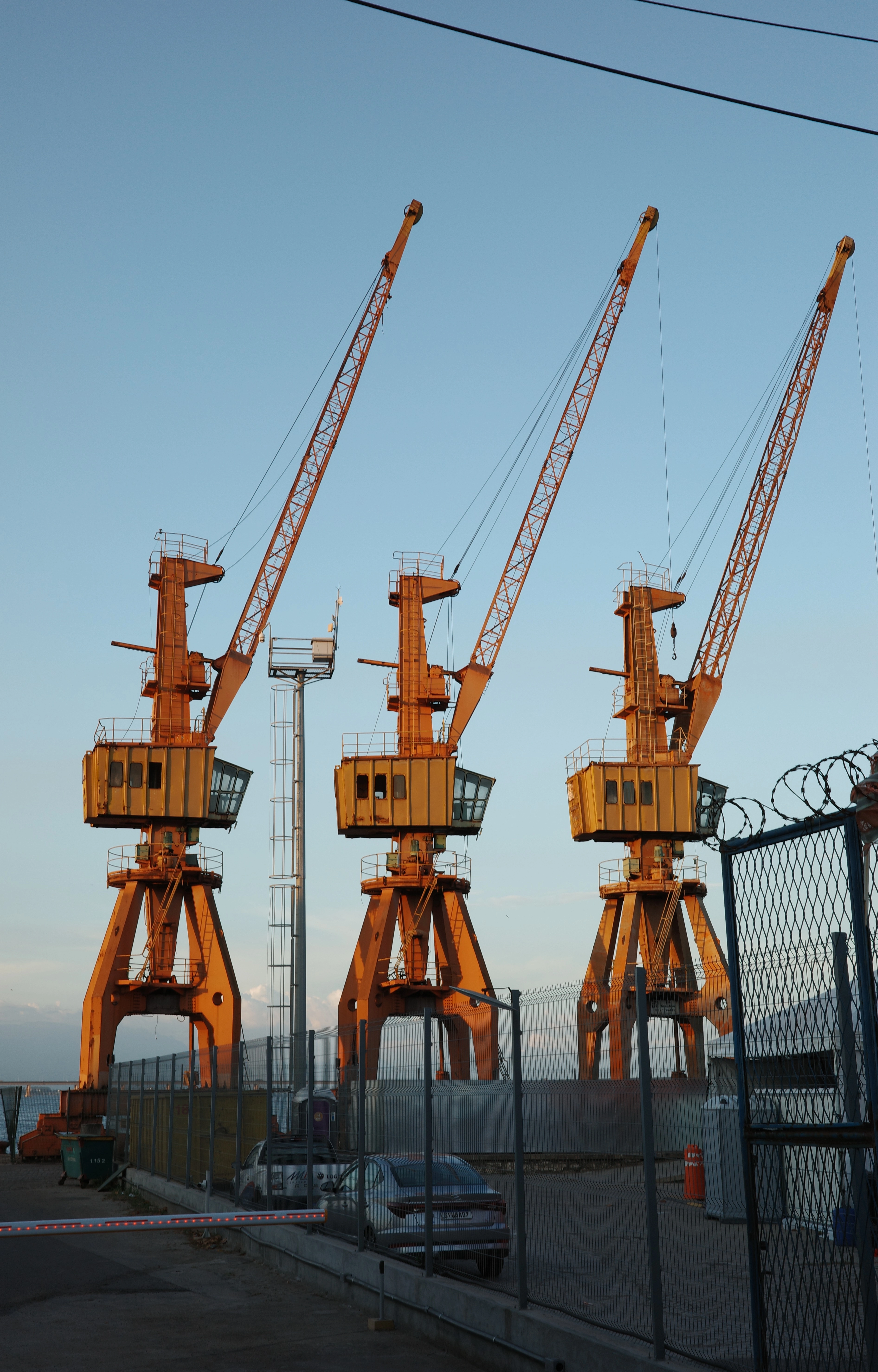 Three yellow port cranes at dusk